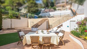 A patio with a table and chairs, a stone staircase, and a view of the surrounding area.
