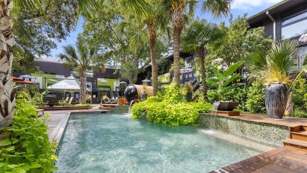 A pool area with a clear water surface, surrounded by lush greenery and palm trees. - Beautiful first-floor 2BR/1.5BA condo near White Rock Lake with resort-style pool, hot tub, cold plunge, dry sauna, and outdoor cardio area—perfect for a relaxing Dallas getaway. (Dallas)