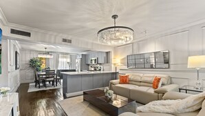 A spacious living area with a large chandelier, a sofa, and a coffee table. - Beautiful first-floor 2BR/1.5BA condo near White Rock Lake with resort-style pool, hot tub, cold plunge, dry sauna, and outdoor cardio area—perfect for a relaxing Dallas getaway. (Dallas)