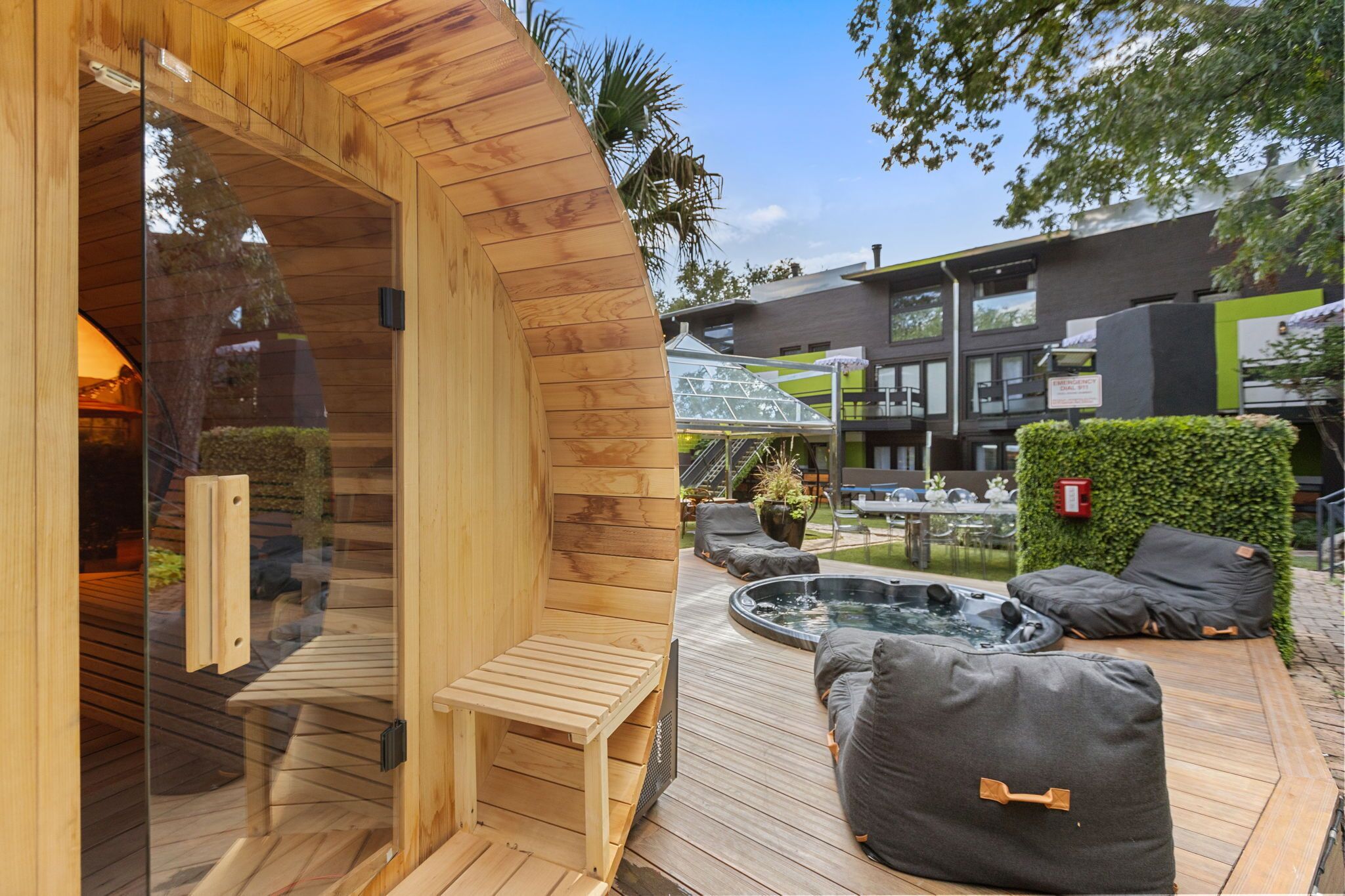 Een houten sauna met een bank en een bubbelbadgedeelte met kussens.