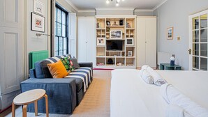 Un dormitorio con cama, sofá, televisor y estantería.