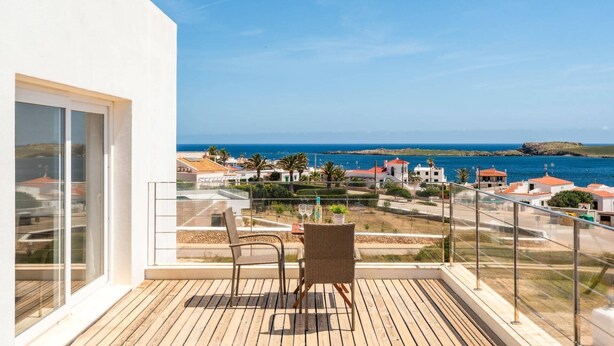 En balkon med havudsigt, en stol og et bord.