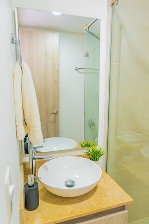 A bathroom with a sink, mirror, towel rack, and a glass shower enclosure. - U-GO Edificio Ocean Drive en Crespo (Cartagena)