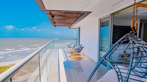 A balcony with a view of the ocean, a hanging chair, and a glass railing. - U-GO Edificio Ocean Drive en Crespo (Cartagena)