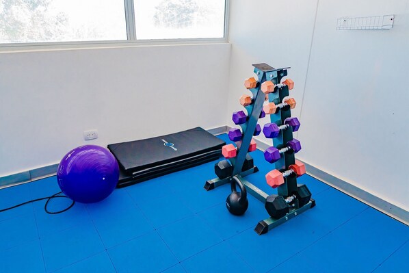 A gym with exercise equipment, a blue mat, and a window.