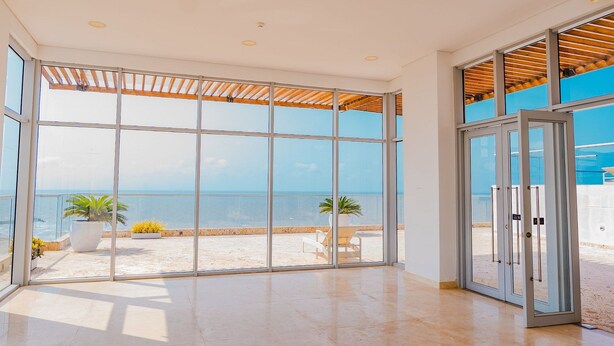 A spacious room with large glass doors leading to a balcony with a view of the sea. - U-GO Edificio Ocean Drive en Crespo (Cartagena)