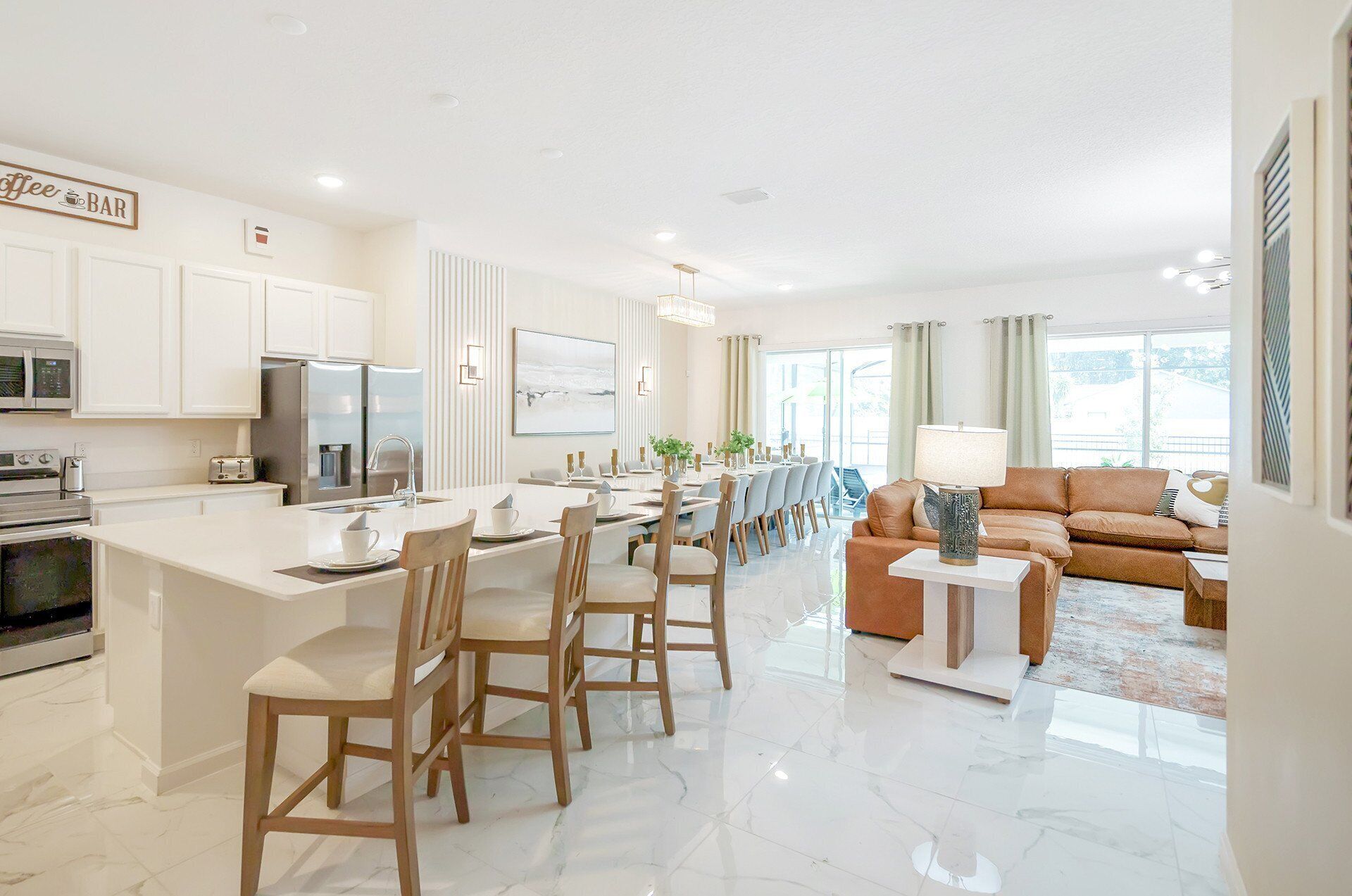 A modern kitchen with white cabinetry, a central island with bar stools, and a dining area with a table and chairs.
