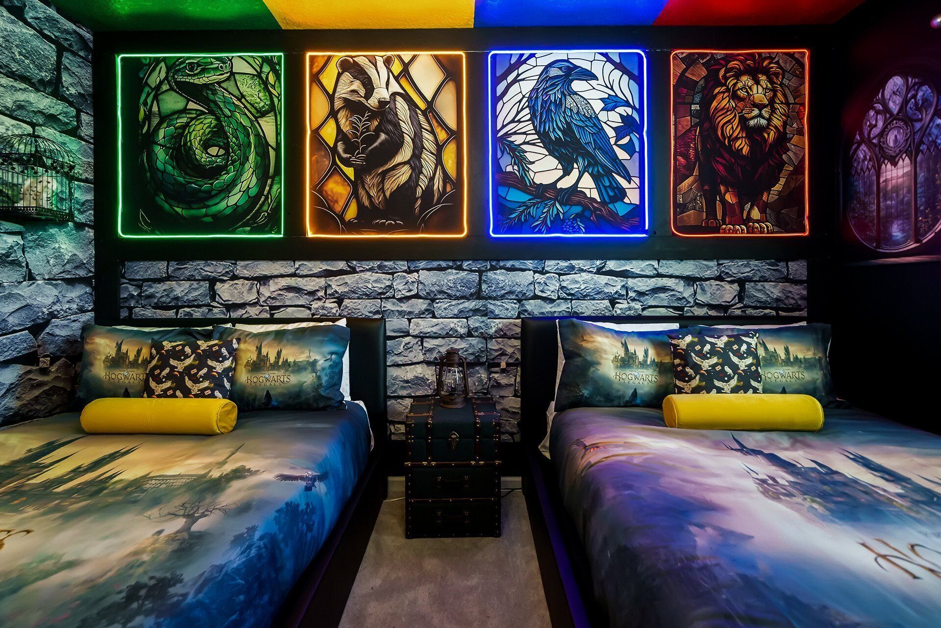 Quarto com duas camas, cada uma com travesseiro com o desenho do castelo de Hogwarts. Acima das camas, quatro painéis de vitral iluminados retratam uma serpente, um texugo, um corvo e um leão.