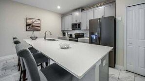 A modern kitchen with a central island, stainless steel appliances, and a minimalist design. - Last Minute Disney! Townhouse with Private Pool. Book Now! #CG3435 (Orlando)