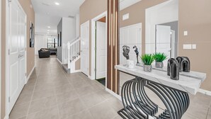 A modern hallway with a marble countertop, potted plants, and a black chair. - Last Minute Disney! Private Pool, Hot Tub, Game Room & Themed Bedrooms. Book Now! #113561 (Orlando)