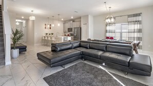 En moderne stue med en modulsofa, et køkken i baggrunden og et spiseområde.