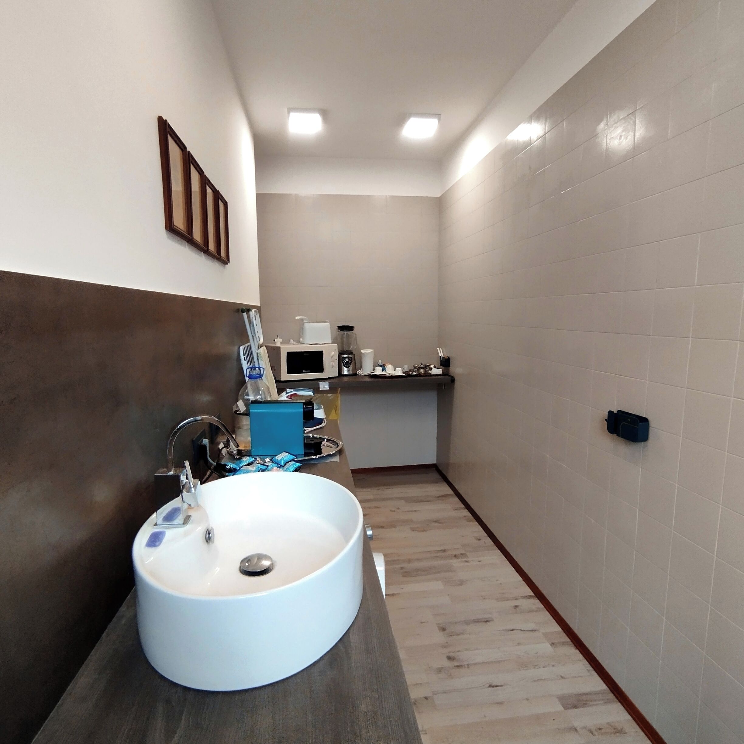 Une petite salle de bain avec un lavabo blanc, un miroir et un petit plan de toilette sur lequel se trouvent un porte-brosse à dents et d’autres articles de toilette.