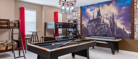 A pool table in a room with a mural of a castle, a bunk bed, and a chandelier.