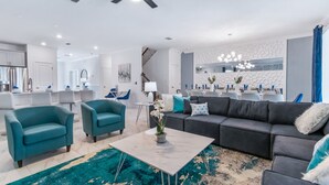 Ein modernes Wohnzimmer mit türkisfarbenen Sessel, einem grauen Sofa und einem Marmor-Couchtisch.