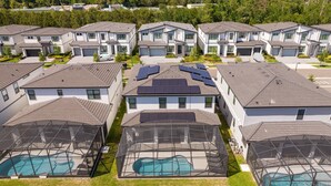 Un barrio residencial con casas modernas, paneles solares en los techos y piscinas con cerramientos de vidrio.
