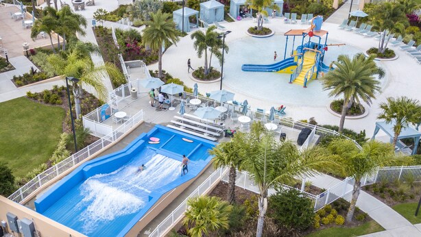 A swimming pool with a water slide, surrounded by palm trees and lounge chairs. - Disney! Private Pool, Hot Tub, Game Room & Themed Bedrooms. Book Now! #Solara567 (Orlando)