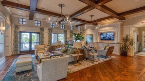 A spacious living room with a high ceiling, wooden beams, a large TV, and comfortable seating. - Disney! Private Pool, Hot Tub, Game Room & Themed Bedrooms. Book Now! #Solara567 (Orlando)