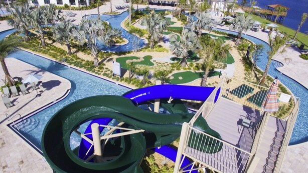 Un resort con un tobogán acuático grande, varias piscinas y un campo de golf.