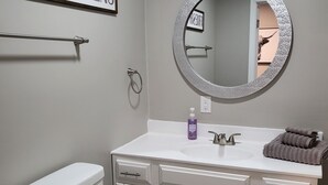 A bathroom with a toilet, a sink with a mirror, and a towel rack.