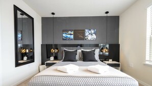 Una camera da letto moderna con un letto grande, un comodino, uno specchio e opere d'arte alle pareti.