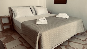 A neatly made bed with a quilted blanket, two pillows, and two folded towels on the bed. - Apartment in the Heart of Tinos Town for 4 Guests (Tinos)