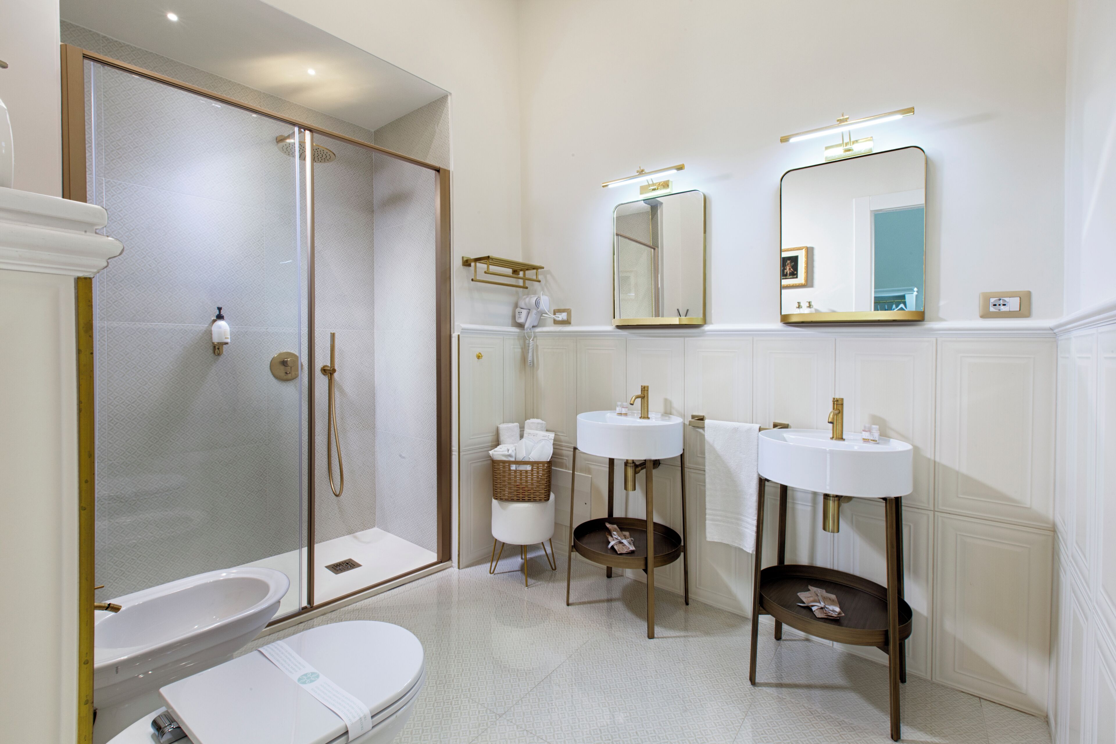 A modern bathroom with a glass-enclosed shower, a toilet, two sinks, and a vanity with a mirror.