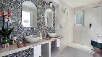 Un baño moderno con un espejo grande, dos lavamanos, ducha y un inodoro.