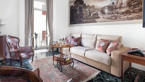 A living room with a sofa, armchairs, a coffee table, and a painting on the wall. - Grace Suites (Sorrento)