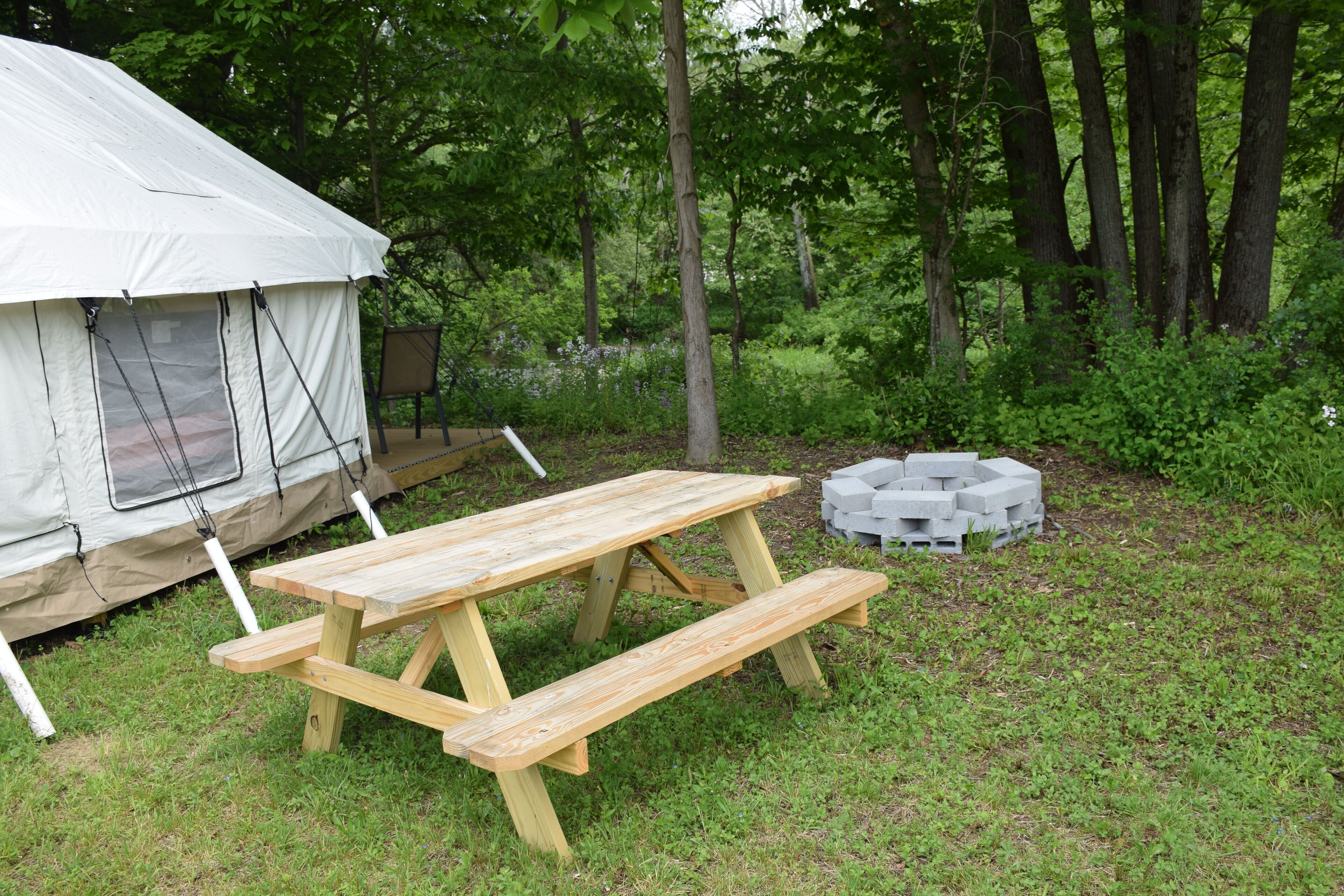 Un terrain de camping équipé d’une tente, d’une table de pique-nique et d’un foyer.