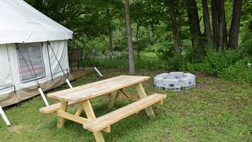 Un terrain de camping équipé d’une tente, d’une table de pique-nique et d’un foyer.