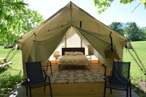 A tent with a bed, two chairs, and a patterned rug. - Peyper Fields Creekside Camp (Newark Valley)