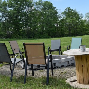 A picnic area with a round wooden table and four chairs. - Peyper Fields Creekside Camp (Newark Valley)