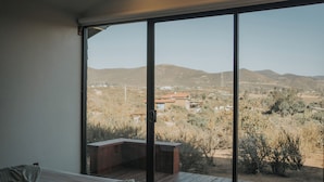 A bedroom with a large sliding glass door leading to an outdoor deck. - Cabins by 7 Valles (Valle de Guadalupe)