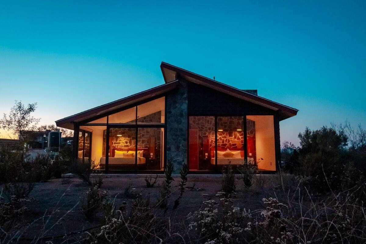 Ein modernes Haus mit großen Glasfenstern, einer Steinfassade und einem gut beleuchteten Innenraum.