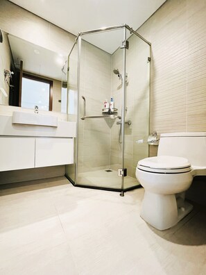 Een moderne badkamer met een douche met glazen wand, een wit toilet en een wastafel met spiegel erboven.