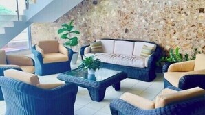 A modern lounge area with wicker furniture, a stone wall, and a staircase.