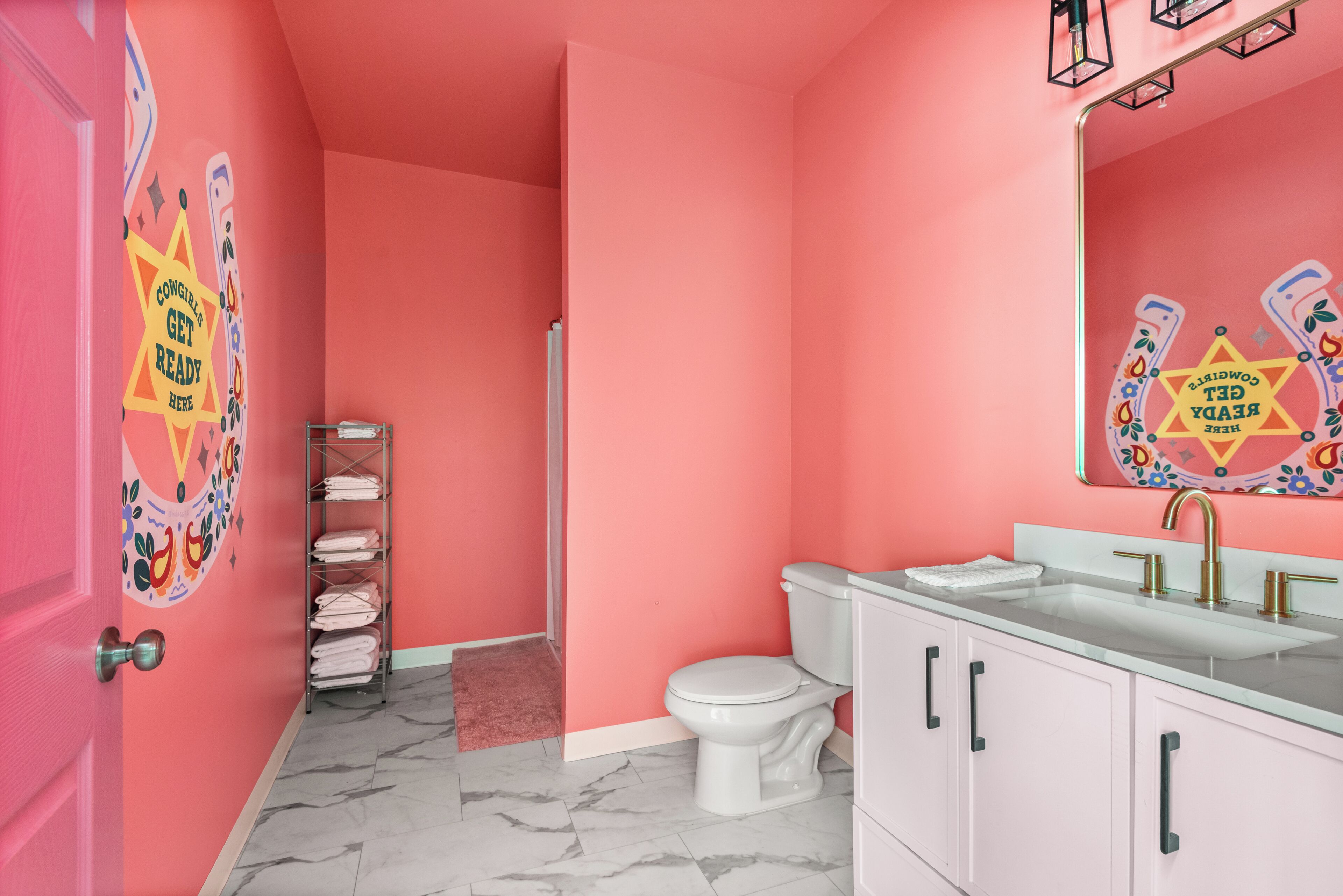 A bathroom with pink walls, a white toilet, a sink with a mirror, and a towel rack.