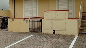 En toetages bygning med balkon, skodder og en lukket indgang.