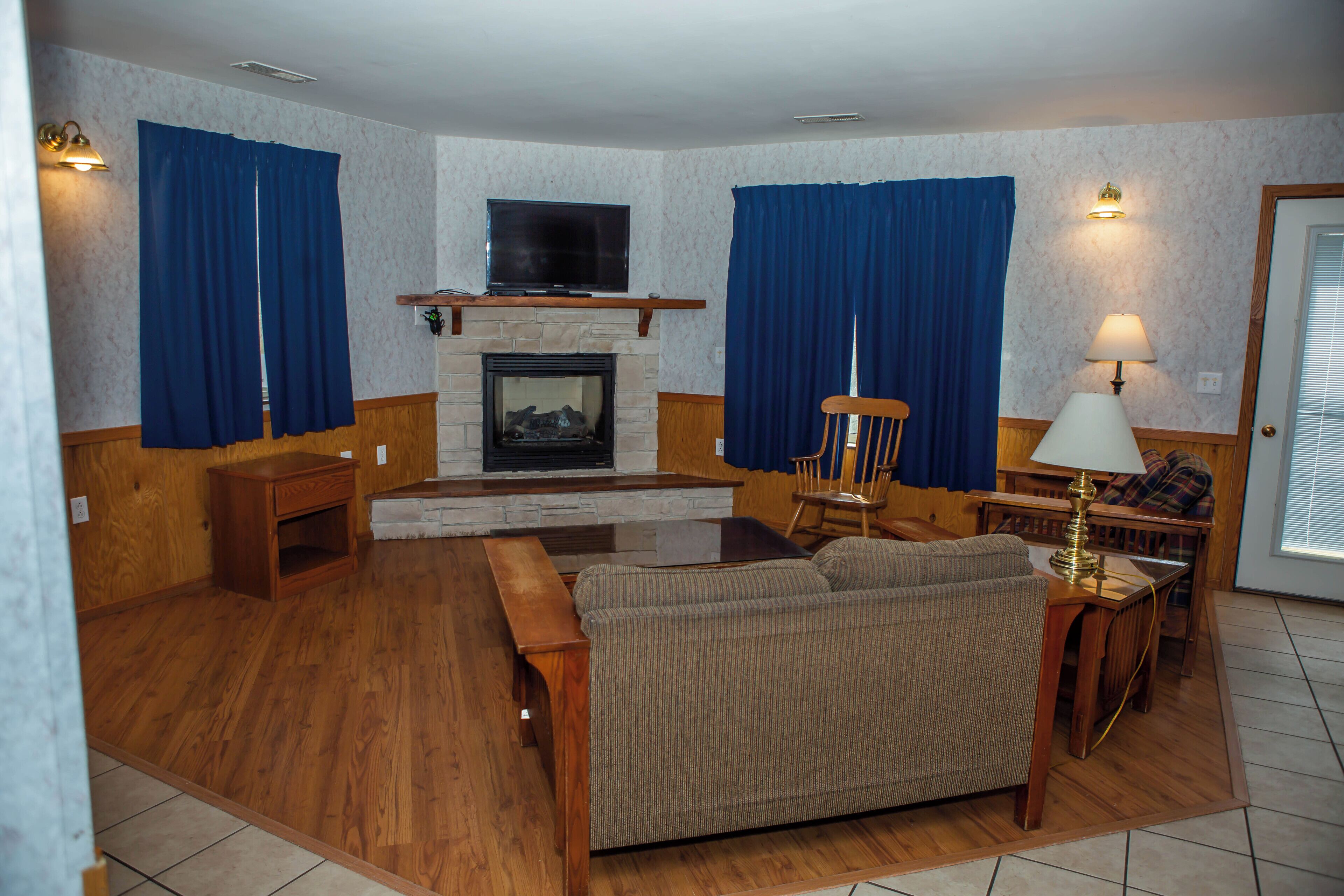 Una sala de estar con chimenea, muebles de madera y televisor.