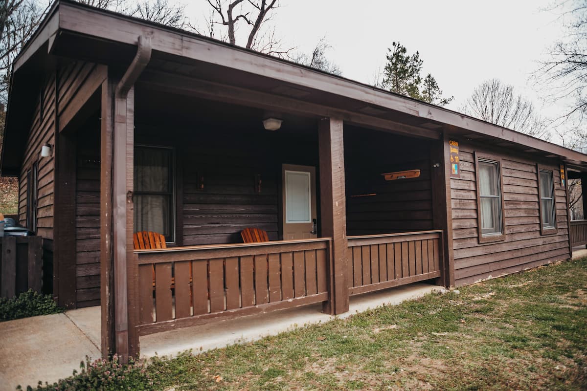 Eine Holzhütte mit Veranda, Tür und Fenstern.