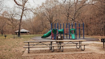 A playground with a slide, climbing structure, and a picnic table area.