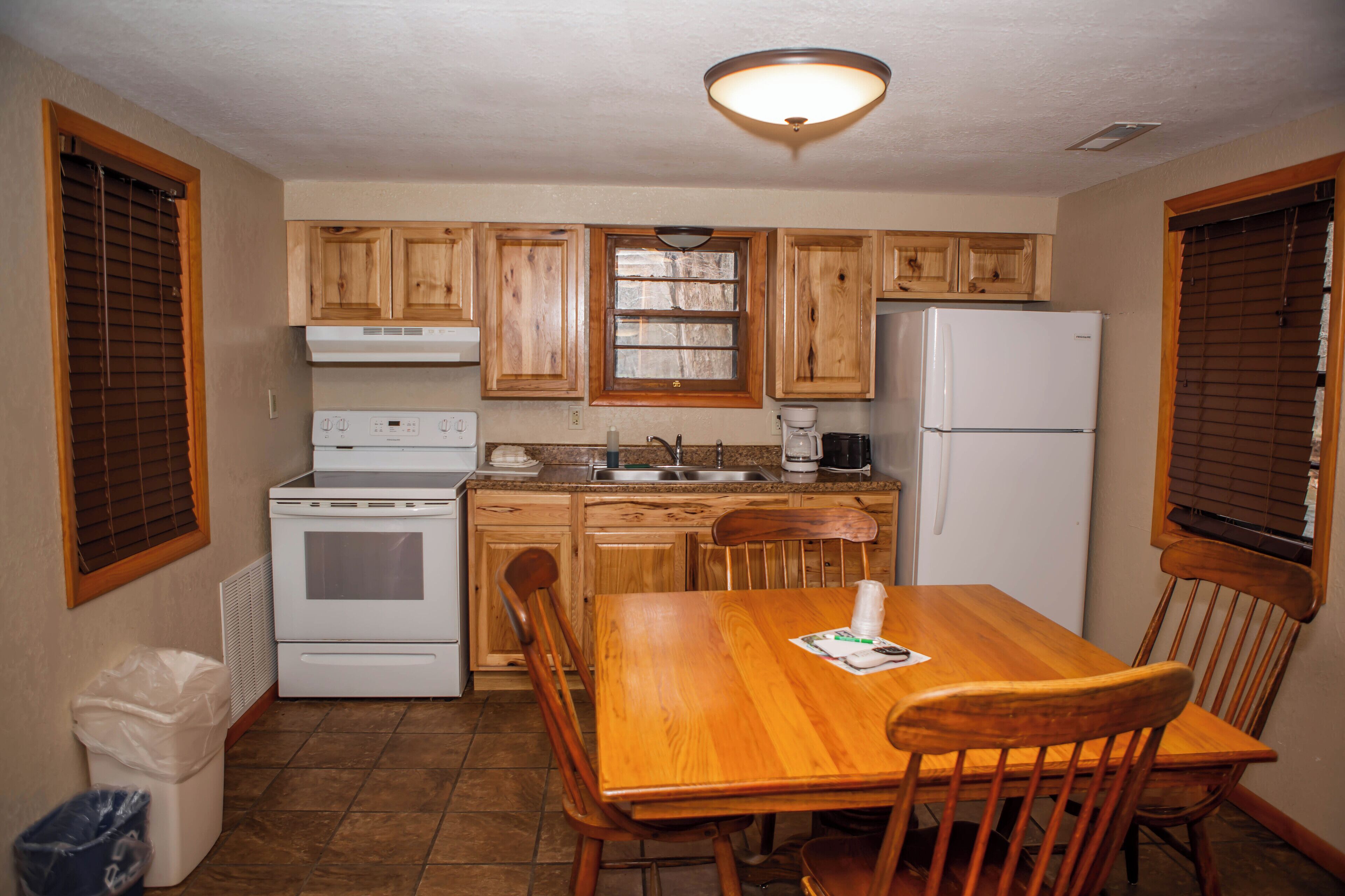Una cocina compacta con armarios de madera, una estufa blanca y una mesa de comedor con sillas.