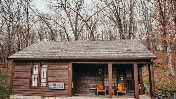 A rustic cabin with a porch, two wooden chairs, and a picnic table. - Montauk Lodge (Salem)