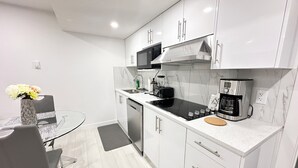 Een moderne keuken met witte kastjes, een zwarte kookplaat en een koffiezetapparaat.