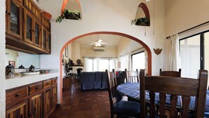 Una cocina amplia con armarios de madera, un comedor con mesa y sillas, y un ventanal que proporciona luz natural.