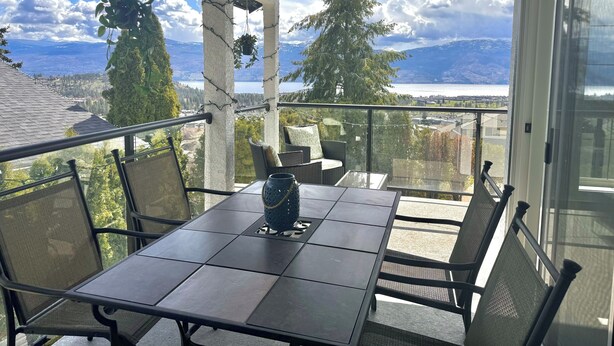 Un espace extérieur aménagé, abrité et doté de tables et de chaises, offrant une vue panoramique sur les montagnes et un lac.
