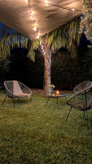 An outdoor seating area with chairs and a table, under a canopy with string lights. - Near the Palermo Airport (PMO): Private villa with a garden, ideal for families (Carini)