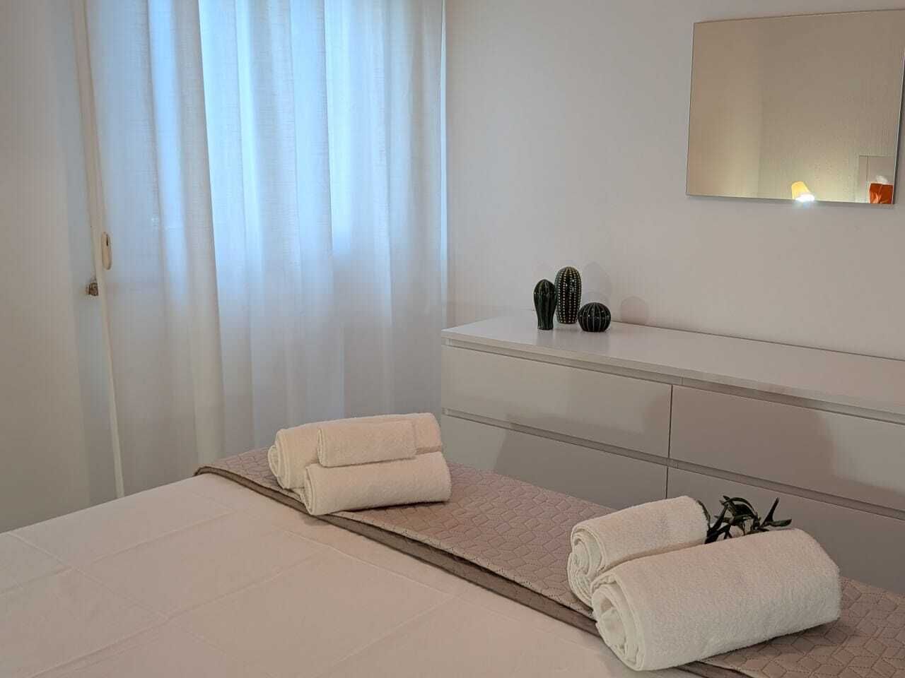 Une chambre d’hôtel avec un lit, une table de chevet avec un miroir et une fenêtre avec des rideaux.