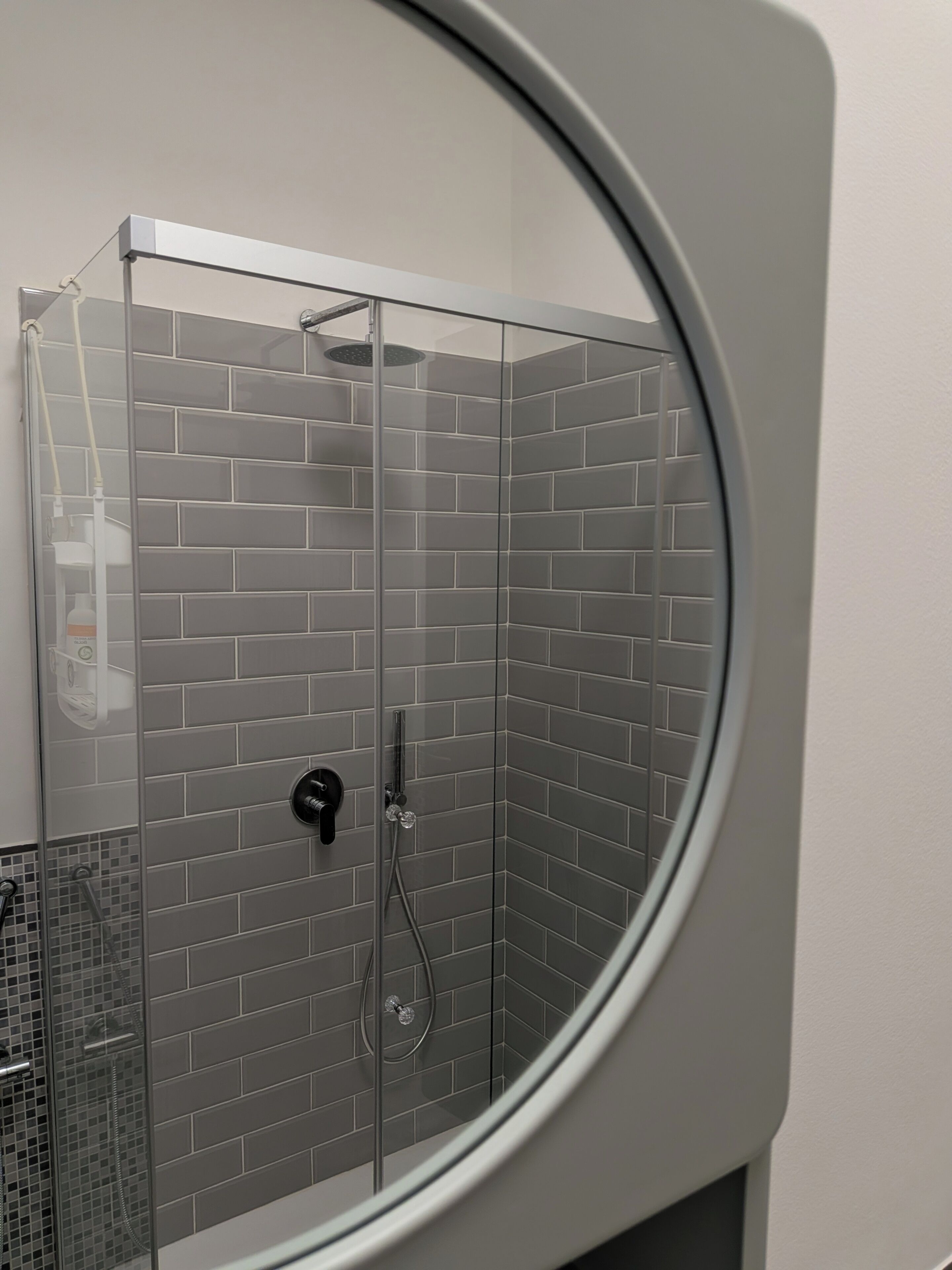 Une douche avec une porte en verre et un mur carrelé.