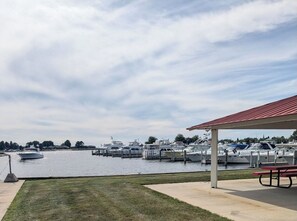 Un puerto deportivo con barcos amarrados, zona de picnic y área con césped.